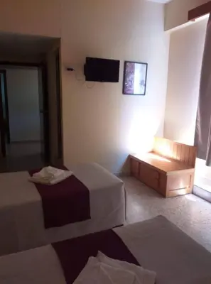 a hotel room with two beds and a television at Minaides Hotel in Kakopetria