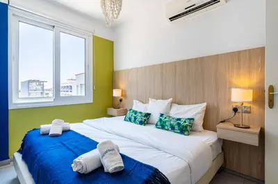 a bedroom with two beds with blue and green walls at Whispering Palms 1-BR Apt By Finikoudes Beach in Larnaka