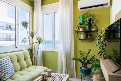a living room with a couch and some plants at Whispering Palms 1-BR Apt By Finikoudes Beach in Larnaka