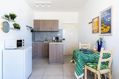 a small kitchen with a table and a refrigerator at Whispering Palms 1-BR Apt By Finikoudes Beach in Larnaka