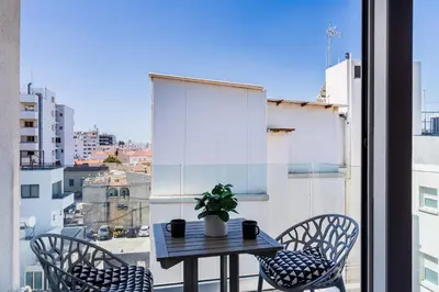 a table and chairs on a balcony with a window at Made with love 1-BR Apt By Finikoudes Beach in Larnaka