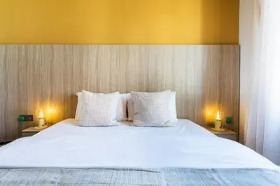 a large bed with white sheets and two lamps on tables at Made with love 1-BR Apt By Finikoudes Beach in Larnaka