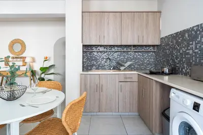 a kitchen with a sink and a table with chairs at Beach Daze 1-BR Apt By Finikoudes Beach in Larnaka