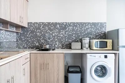 a kitchen with a washing machine and a microwave at Beach Daze 1-BR Apt By Finikoudes Beach in Larnaka