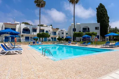 a swimming pool with chairs and umbrellas in a resort at Sea Breeze 1-BR Apt in Pyla in Pyla