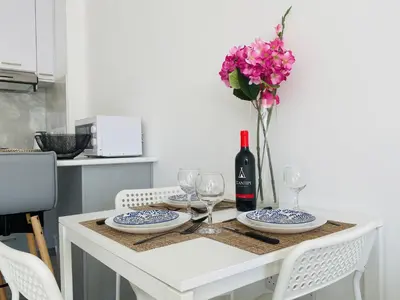 a table with a bottle of wine and a vase of flowers at Pink Flamingo 1-BR apartment in Larnaca in Larnaka