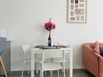 a white dining room table with chairs and a vase of flowers at Pink Flamingo 1-BR apartment in Larnaca in Larnaka