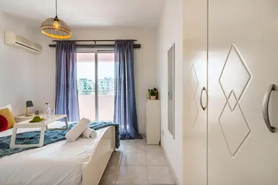a bedroom with a bed and a table and a window at Sweet retreat 2-BR Apartment in Mackenzie in Larnaka