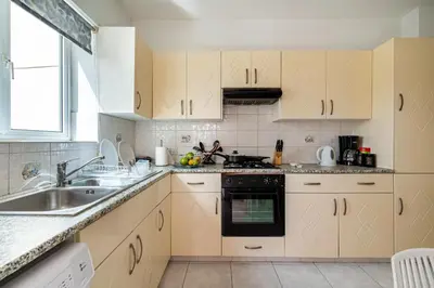 a kitchen with white cabinets and a sink at Sweet retreat 2-BR Apartment in Mackenzie in Larnaka