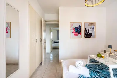 a white living room with a table and a mirror at Sweet retreat 2-BR Apartment in Mackenzie in Larnaka