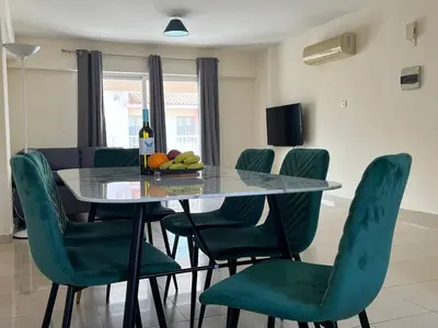 a dining room with a table and green chairs at Greek Harmony Apartment in Paralimni