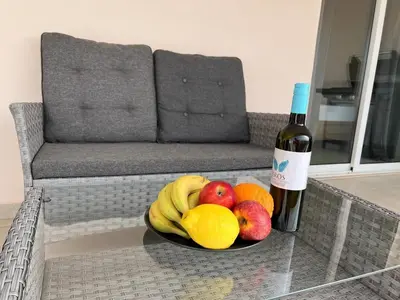 a bowl of fruit on a table with a bottle of wine at Greek Harmony Apartment in Paralimni
