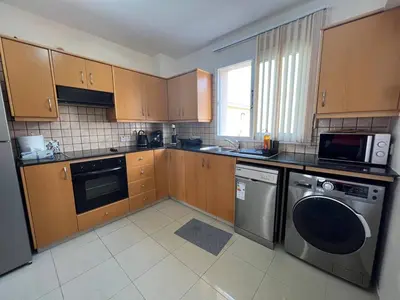 a kitchen with wooden cabinets and a washer and dryer at Greek Harmony Apartment in Paralimni