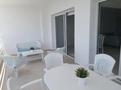 a white living room with white chairs and a table at Dinglis Residences 31 in Larnaka