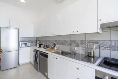 a kitchen with white cabinets and a sink and a dishwasher at To Hani - Kamara Maisonette in Nicosia