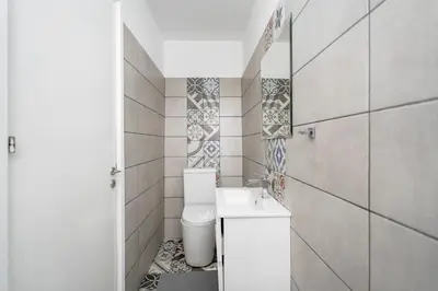 a white bathroom with a toilet and a sink at To Hani - Small Studio in Nicosia