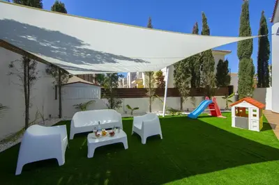 a patio with white chairs and a table and a playground at Tsokkos Family Villa - Pool Garden 2' Walk to Beach in Protaras