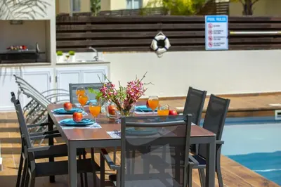 a wooden table with chairs and a table with oranges on it at Tsokkos Family Villa - Pool Garden 2' Walk to Beach in Protaras