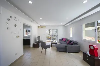 a living room with a couch and a clock on the wall at Tsokkos Family Villa - Pool Garden 2' Walk to Beach in Protaras