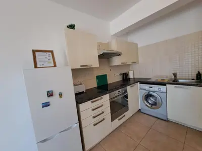 a kitchen with a white refrigerator and a dishwasher at AFRODITI APARTMENTs in Pervolia