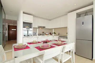 a white kitchen with a dining table and a refrigerator at Villa Napa Seaside in Ayia Napa