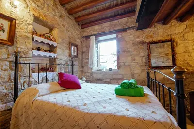 a bedroom with a bed with colorful pillows on it at Constantias stone houses in Lofou