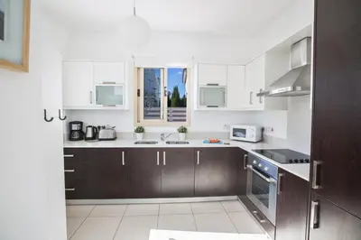 a kitchen with white walls and brown cabinets at Palm Villa 17 in Protaras