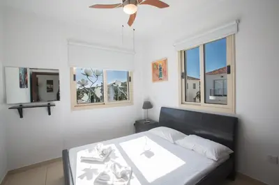 a bedroom with a bed with a ceiling fan and windows at Palm Villa 17 in Protaras