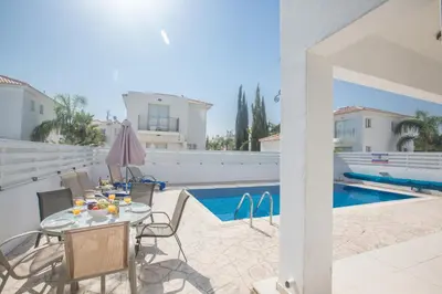 a patio with a table and chairs next to a pool at Palm Villa 17 in Protaras