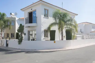 a white house with palm trees in front of it at Palm Villa 17 in Protaras