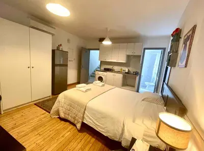 a bedroom with a white bed and a kitchen at Irida - Studio Down Town Nicosia in Nicosia