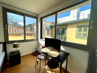a room with a table and chairs and windows at Irida - Studio Down Town Nicosia in Nicosia