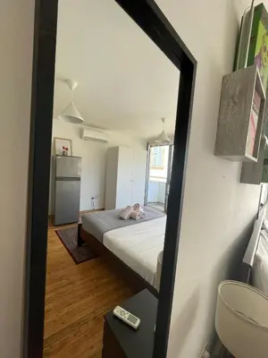 a mirror reflecting a bedroom with a bed and a sink at Irida - Studio Down Town Nicosia in Nicosia