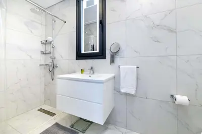 a white bathroom with a sink and a shower at By The Beach - Royal Sapphire Villa in Protaras