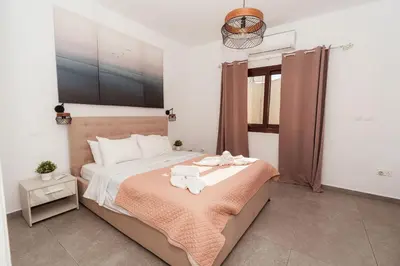 a bedroom with a large bed with a orange blanket at SerenityOne - Centrally located One Bedroom Apt in Ayia Napa