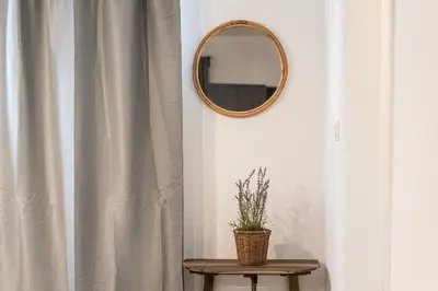 a mirror on a wall next to a table with a plant at SerenityOne - Centrally located One Bedroom Apt in Ayia Napa