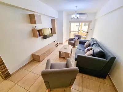 a living room with a blue couch and chairs at Sunbay City Rooms in Larnaka