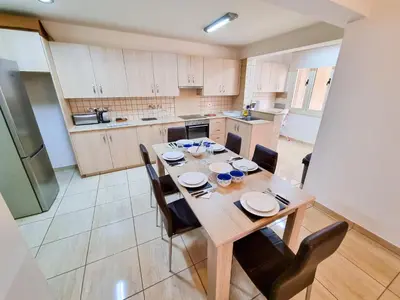 a large kitchen with a wooden table and chairs at Sunbay City Rooms in Larnaka