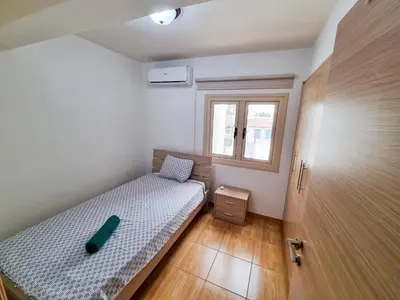 a small bedroom with a bed and a window at Sunbay City Rooms in Larnaka
