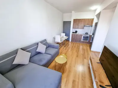 a living room with a blue couch and a kitchen at Springfield Park Apartment in Larnaka