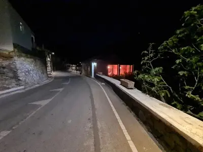 an empty road at night with a building in the background at Elpiniki's Old House in Kalopanayiotis