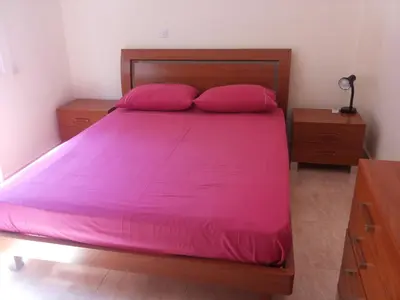 a bedroom with a bed with pink sheets and two night stands at Katikies 19 in Pissouri