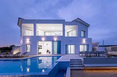 a large house with a swimming pool in front of it at Mediterranean Dream Beachfront Villa in Larnaka