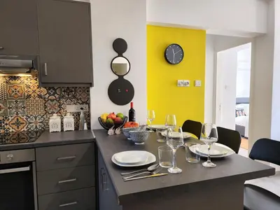 a kitchen with a table with plates and wine glasses at Lazuli Frida Two Bedroom Apt in Larnaka
