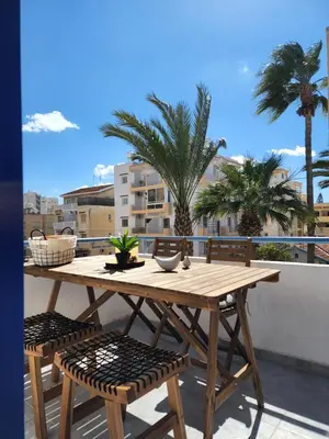 a wooden table and chairs on a balcony with palm trees at Lazuli Frida Two Bedroom Apt in Larnaka