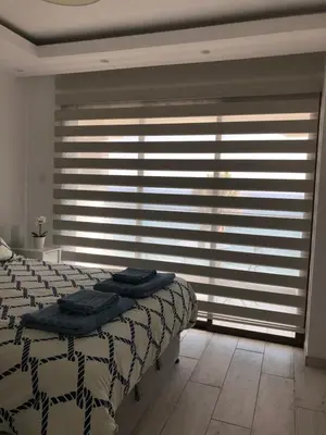 a bedroom with a bed and a window with blinds at Blue Escape (Beach Seafront) in Larnaka