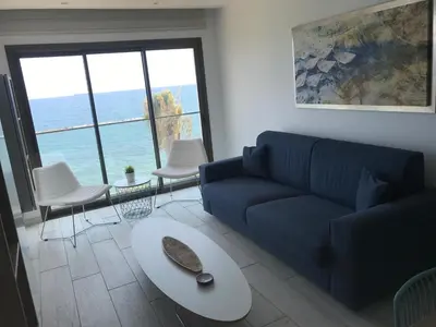 a living room with a blue couch and a table at Blue Escape (Beach Seafront) in Larnaka