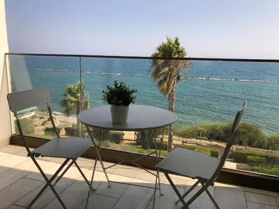 a table and chairs on a balcony with a view of the ocean at Blue Escape (Beach Seafront) in Larnaka