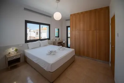 a bedroom with a large white bed and a wooden cabinet at Luxury Villa Agathoula in Protaras