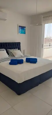 a large bed with blue pillows on top of it at Nissi 3 Amazing Sea View Apartment in Ayia Napa